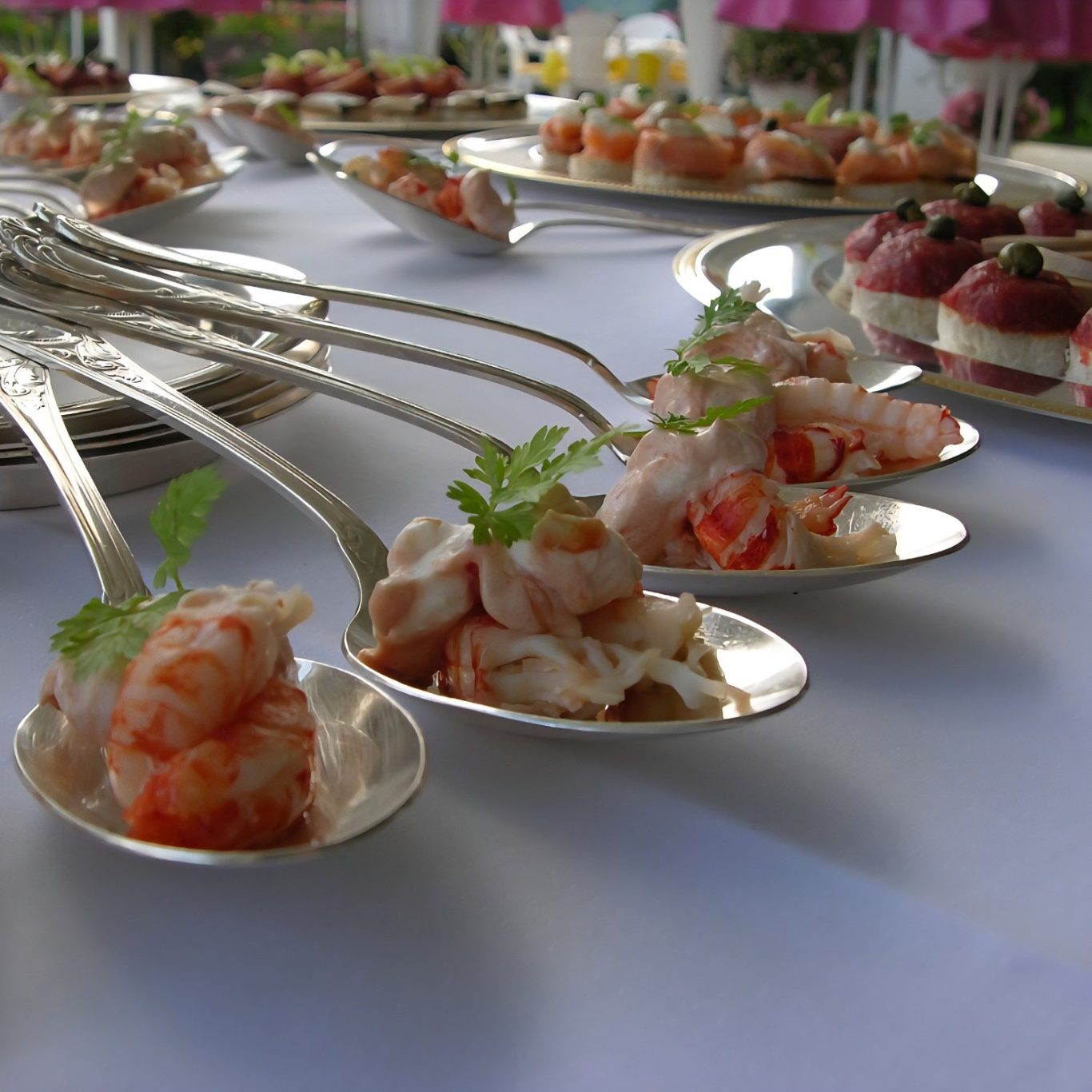 Fein angerichtete Löffel mit Garnelen und frischen Kräutern auf einer stilvollen Catering-Tafel